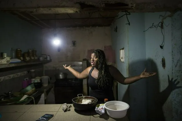 In this February 14, 2019 photo, Dugleidi Salcedo complains to a neighbor about the high price of food as she prepares arepas for her three sons in her kitchen in the Petare slum, in Caracas, Venezuela. Hunger drove Salcedo to send her four-year-old daughter to live with an aunt when she could no longer feed her. “My boys cry”, the single mother of four said. “But they resist more than her when I tell them that there’s no food”. (Photo by Rodrigo Abd/AP Photo)