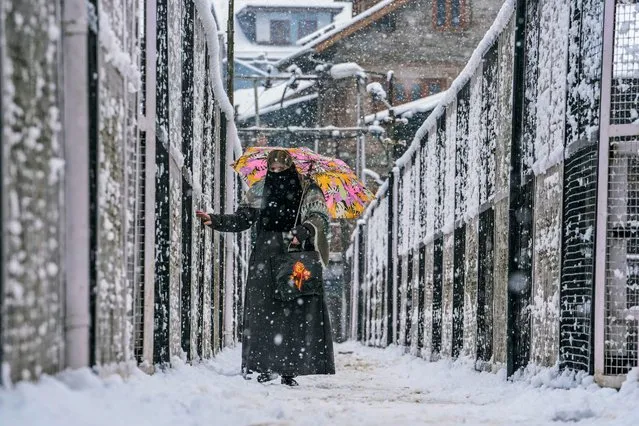 A woman crosses a slippery bridge as it snows on the second consecutive day in Srinagar, Indian controlled Kashmir, Sunday, February 4, 2024. (Photo by Mukhtar Khan/AP Photo)