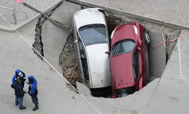 A view of two parked cars, a Nissan Juke and a Toyota Corolla Spacio, swallowed by a sinkhole on Frunze Street in Novosibirsk, Russia on October 13, 2021. (Photo by Kirill Kukhmar/TASS)