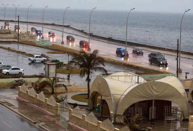 The convoy carrying President Barack Obama and his family drives in the rain along the Malecon sea wall, past an artisan market in Havana, Cuba, Sunday, March 20, 2016. (Photo by Desmond Boylan/AP Photo)