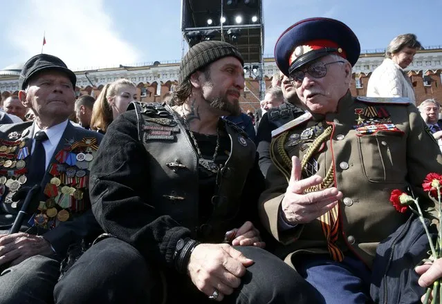 Leader of the motorcycling club Night Wolves Alexander Zaldostanov (C), nicknamed “Khirurg” (Surgeon), talks to a veteran prior to the Victory Day parade at Red Square in Moscow, Russia, May 9, 2015. (Photo by Grigory Dukor/Reuters)
