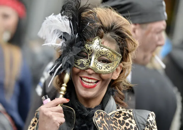 A woman smiles behind her mask when tens of thousands revelers dressed in carnival costumes celebrate the start of the street-carnival on the so called “Old Women's Day” in the party capital Cologne, Germany, Thursday, February 27, 2014. (Photo by Martin Meissner/AP Photo)
