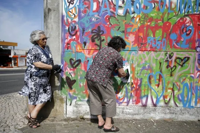 Women spray their designs on a wall during a graffiti class offered by the LATA 65 organization in Lisbon, Portugal May 14, 2015. (Photo by Rafael Marchante/Reuters)
