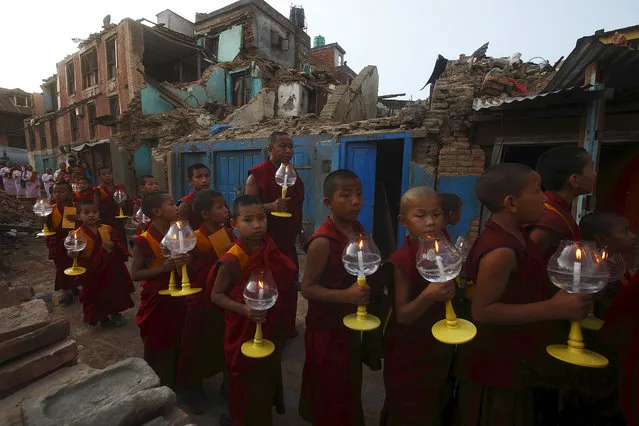 Buddhist monks hold candles as they walk past collapsed buildings during a candlelight vigil as they pray for the earthquakes to cease, in Kathmandu, Nepal, May 20, 2015. (Photo by Gopen Rai/Reuters)