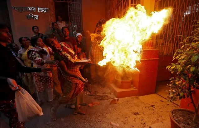 A Hindu holy man throws fire towards the gate of a temple as part of a ritual ending a religious procession held to mark the Gajan festival in Kolkata, India, April 12, 2016. (Photo by Rupak De Chowdhuri/Reuters)