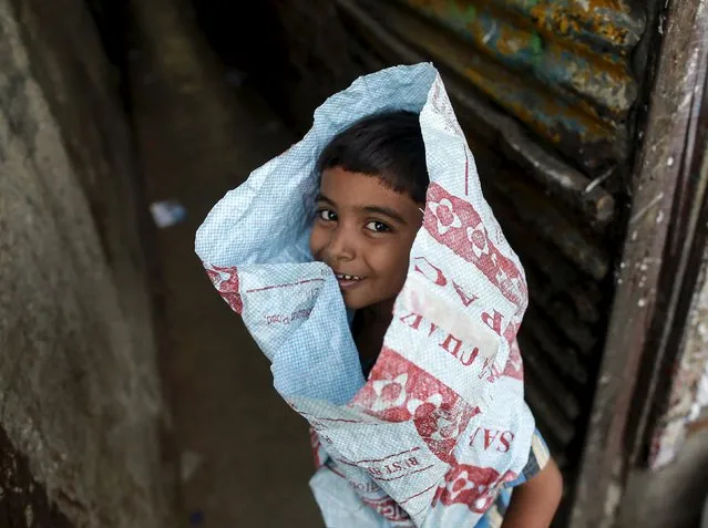 A boy wearing a plastic sack plays in an alley in a slum in Mumbai, India, April 20, 2016. (Photo by Danish Siddiqui/Reuters)