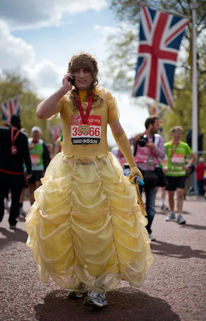 A man in a dress recovers after crossing the finish line of the 2012 London Marathon on April 22, 2012. (Photo by Leon Neal/AFP Photo)