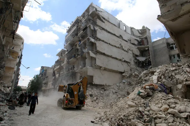 A front loader operates at a site hit by airstrikes in the rebel held area of al-Sukari district of Aleppo, Syria, April 28, 2016. (Photo by Abdalrhman Ismail/Reuters)