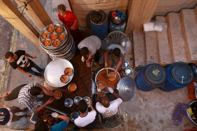 Volunteers prepare food as people wait to eat their Iftar (breaking of fast) meal at tables set up by a charity during the holy fasting month of Ramadan in Benghazi, Libya  June 27, 2015. (Photo by Esam Omran Al-Fetori/Reuters)