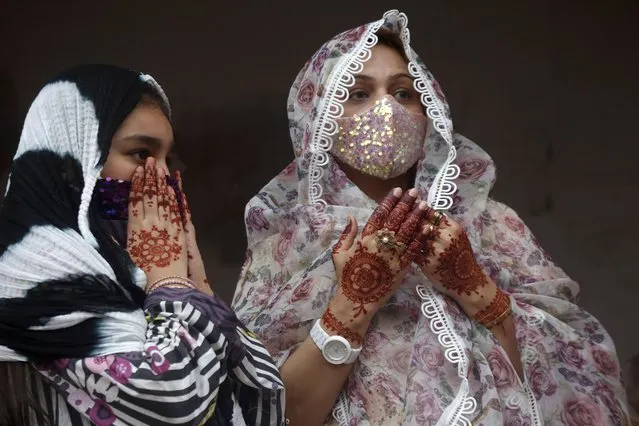 Muslim women with their hands painted with traditional henna pray during an Eid al-Fitr prayer at historical Badshahi mosque, in Lahore, Pakistan, Thursday, May 13, 2021. Millions of Muslims across the world are marking a muted and gloomy holiday of Eid al-Fitr, the end of the fasting month of Ramadan, a usually joyous three-day celebration that has been significantly toned down as coronavirus cases soar. (Photo by K.M. Chaudary/AP Photo)