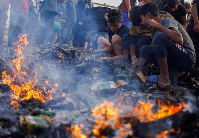 Palestinians search for food among burnt debris in the aftermath of an Israeli strike on an area designated for displaced people, in Rafah in the southern Gaza Strip on May 27, 2024. (Photo by Mohammed Salem/Reuters)