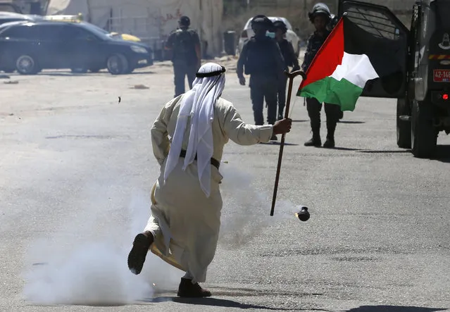 A Palestinian demonstrator runs past a tear gas canister launched by Israeli forces during a protest in solidarity with Palestinian prisoners held in Israeli jails near Israel's Ofer Prison in the Israeli-occupied West Bank on August 22, 2019. (Photo by Abbas Momani/AFP Photo)