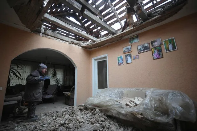 A local resident of the Ukrainian-controlled village of Stanytsia Luhanska, Luhansk region, gestures as she cleans up debris from her home after the shelling by Russia-Backed separatists on February 18, 2022. Eastern Ukraine was experiencing new shelling on February 18, 2022, the Ukrainian army and pro-Russian separatists accusing each other of using heavy weapons, an upsurge in violence that feeds fears of Russian invasion. (Photo by Aleksey Filippov/AFP Photo)
