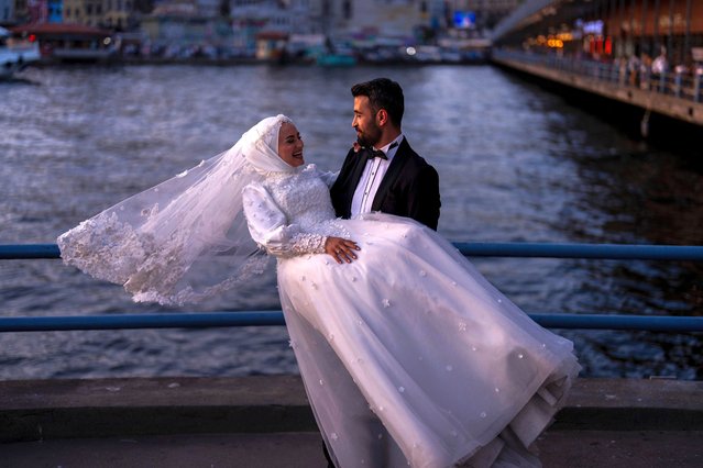 A young couple pose during a photo session at Galata bridge in Istanbul, Turkey, Monday, June 3, 2024. The landmark is a popular location for photograph sessions of couples who are about to or just married. (Photo by Francisco Seco/AP Photo)