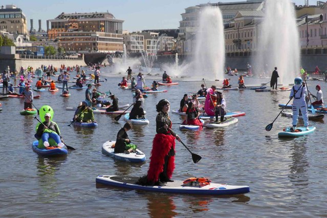 People steer their SUP boards along the Moscow River Channel during a SUP (Stand Up Paddle)-Surfing festival in Moscow, Russia, Saturday, May 25, 2024. (Photo by Vasily Kuzmichonok/Moscow News Agency via AP Photo)