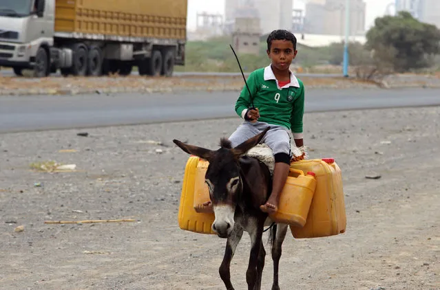 A Yemeni boy rides a donkey carrying plastic containers full of water in an impoverished coastal village on the outskirts of the Yemeni port city of Hodeidah, on April 17, 2017, as Yemenis continue continue to suffer from an ongoing wide spread disruption of water supplies. (Photo by AFP Photo/Stringer)