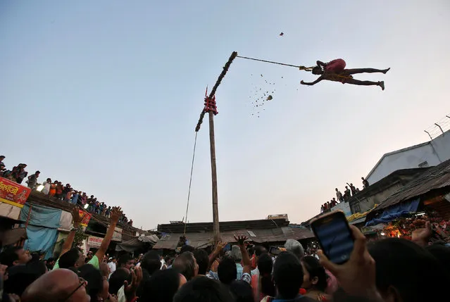 A Hindu devotee hangs from a rope and throws offerings for people to catch during the “Chadak” ritual, which is held to worship the Hindu deity Lord Shiva, in Kolkata, April 14, 2017. (Photo by Rupak De Chowdhuri/Reuters)