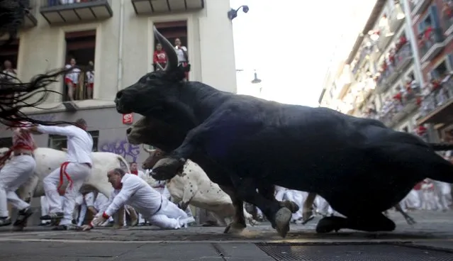 A Garcigrande fighting bull slides at the Mercaderes curve during the seventh running of the bulls of the San Fermin festival in Pamplona, northern Spain, July 13, 2015. (Photo by Joseba Etxaburu/Reuters)