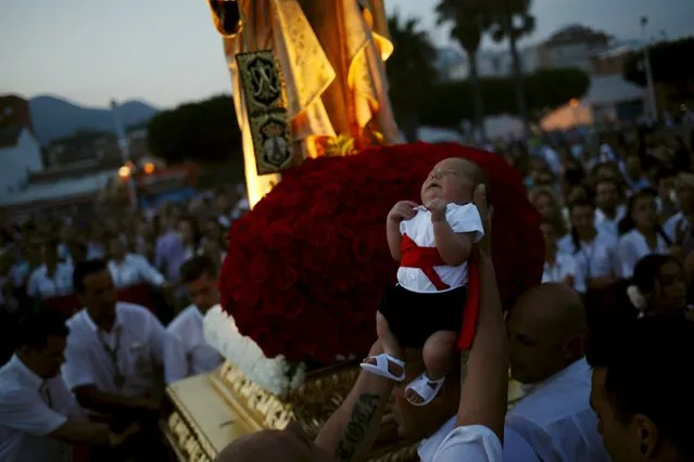 A man holds a child as they take part in the procession of the El Carmen Virgin (rear) being carried into the sea in Malaga July 16, 2015. (Photo by Jon Nazca/Reuters)