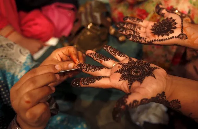 A girl gets her hands decorated with traditional henna patterns at a roadside stall ahead of Eid-al Fitr to mark the end of the holy fasting month of Ramadan in Karachi, Pakistan, July 17, 2015. (Photo by Akhtar Soomro/Reuters)