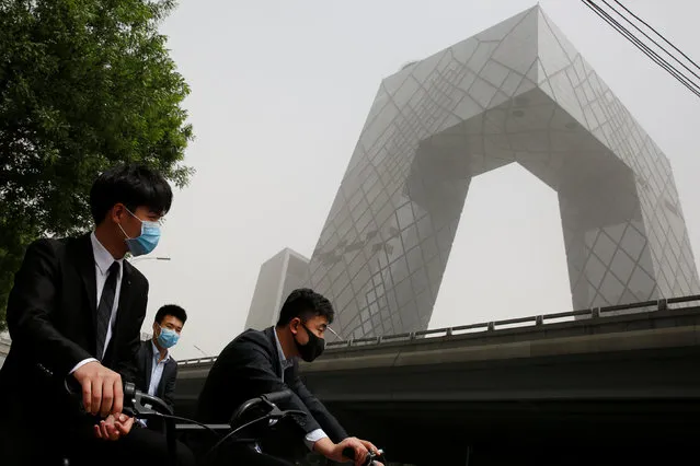 People wear face masks as they wait to cross a street near the China Central Television (CCTV) headquarters during a dust storm in Beijing, China May 4, 2017. (Photo by Thomas Peter/Reuters)