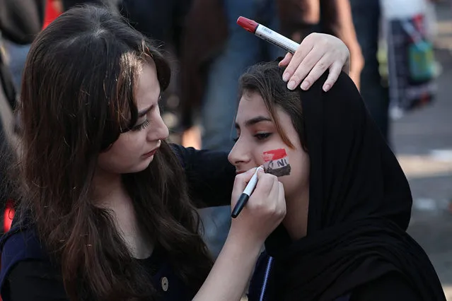 A protester gets her face painted with the colors of the Iraqi flag during ongoing anti-government protests at Tahrir square in Baghdad, Iraq, Thursday, October 31, 2019. (Photo by Hadi Mizban/AP Photo)