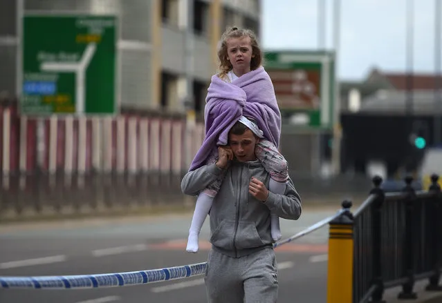 A man carries a young girl on his shoulders near Victoria station in Manchester, northwest England on May 23, 2017. Twenty two people have been killed and dozens injured in Britain's deadliest terror attack in over a decade after a suspected suicide bomber targeted fans leaving a concert of US singer Ariana Grande in Manchester. (Photo by Oli Scarff/AFP Photo)