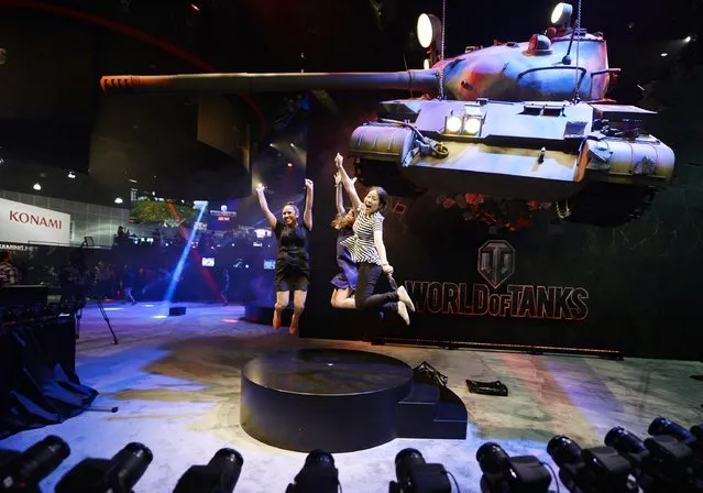 Attendees Priscilla Padilla (L-R), Sacha Tank and Stella Yeo get their picture taken in front of a mock battle tank, promoting the new multiplayer action game "World of Tanks", in the Ubisoft booth at the 2014 Electronic Entertainment Expo, known as E3, in Los Angeles, June 10, 2014.  REUTERS/Kevork Djansezian