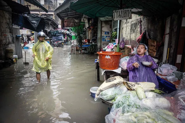Shopkeepers wait for water to recede after heavy rainfall in Bangkok, Thailand on May 30, 2017. (Photo by Lillian Suwanrumpha/AFP Photo)