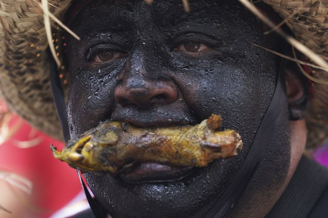 A person taking part in a reenactment of the Battle of Puebla holds a chicken's head in his mouth, during a Cinco de Mayo celebration, in Mexico City, Friday, May 5, 2023. On May 5, 1862, Mexican forces loyal to Benito Juarez defeated French troops sent by Napoleon III in the Battle of Puebla. (Photo by Marco Ugarte/AP Photo)