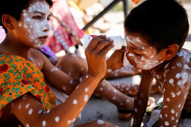 Saul, 11, paints the face of Santiago, 4, as they take part in Good Friday celebrations in the Tarahumara neighborhood of Ciudad Juarez, Mexico on April 15, 2022. (Photo by Jose Luis Gonzalez/Reuters)