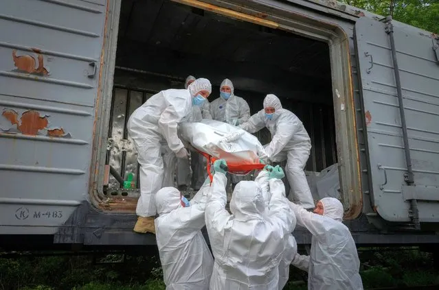 Ukrainian servicemen load bodies of Russian soldiers in to a railway refrigerator carriage in Kyiv, Ukraine, Friday, May 13, 2022. (Photo by Efrem Lukatsky/AP Photo)