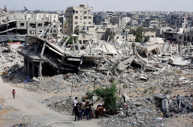 Palestinians sit next to the rubble of houses destroyed in Israel's military offensive, amid the ongoing conflict between Israel and Hamas, in Khan Younis in the southern Gaza Strip on October 7, 2024. (Photo by Mohammed Salem/Reuters)