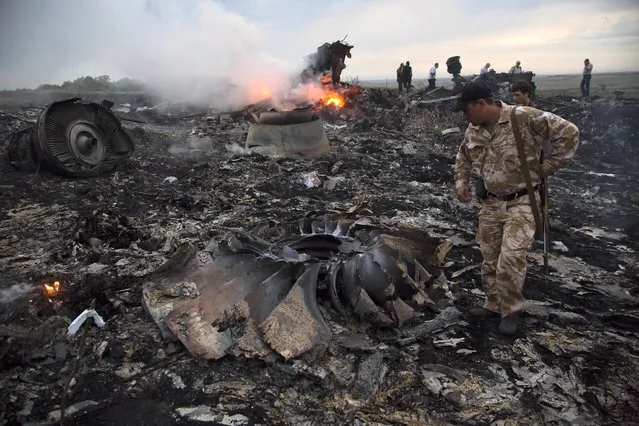 People walk amongst the debris at the crash site of a passenger plane near the village of Grabovo, Ukraine, Thursday, July 17, 2014. Ukraine said a passenger plane carrying 295 people was shot down Thursday as it flew over the country, and both the government and the pro-Russia separatists fighting in the region denied any responsibility for downing the plane. (Photo by Dmitry Lovetsky/AP Photo)