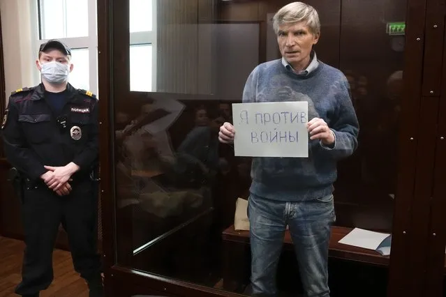 Alexei Gorinov holds a sign “I am against the war” standing in a cage during hearing in the courtroom in Moscow, Russia, Tuesday, June 21, 2022. Moscow's Meshchansky District Court ruled Tuesday that Alexei Gorinov, a member of the municipal council in one of Moscow's districts, should stay in custody pending his trial on charges of discrediting the country's armed forces. (Photo by Alexander Zemlianichenko/AP Photo)