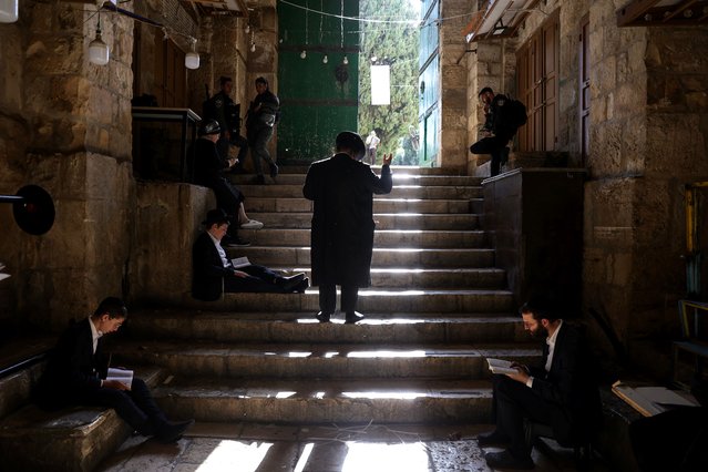 Israeli police officers guard the door leading to Al-Aqsa Mosque compound as Orthodox Jews pray and read from the book of Eicha (Book of Lamentations) to mark Tisha B'av, near The Western Wall, in the Old City of Jerusalem, 27 July 2023. In Judaism, the Tisha B'Av is an annual fast day to mark the destruction of the first and the second temple by the Babylonian and the Roman Empires in Jerusalem. During Tisha B'av, Ultra-Orthodox Jews stay up all night and sleep at the Western Wall as they recite lamentations focusing on the destruction of the ancient temple, that was located on the other side of the ancient wall, on the Temple Mount. (Photo by Abir Sultan/EPA/EFE/Rex Features/Shutterstock)