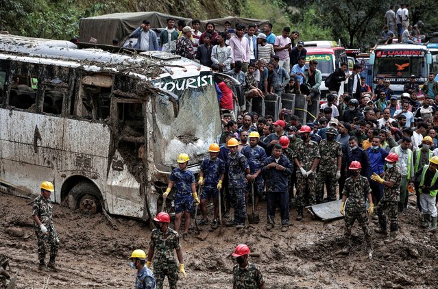 People stranded at the Tribhuwan Highway look on as rescue personnel work to retrieve the bodies of the victims from a landslide triggered by heavy rainfall in Dhading, Nepal, on September 29, 2024. (Photo by Navesh Chitrakar/Reuters)