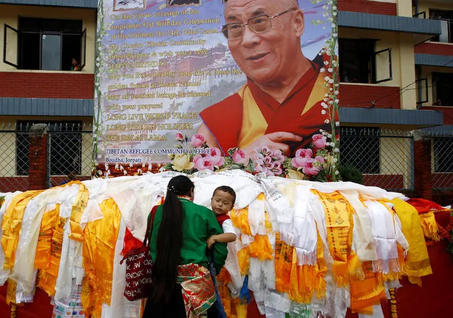 A Tibetan woman offers prayers as she holds a child in front of the portrait of Dalai Lama during his birthday celebration in Kathmandu, Nepal, July 6, 2016. (Photo by Navesh Chitrakar/Reuters)