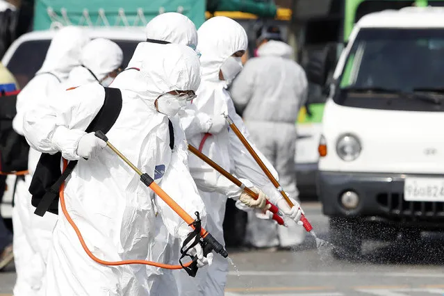 Workers wearing protective gears spray disinfectant as a precaution against the coronavirus at a bus garage in Gwangju, South Korea, Tuesday, March 3, 2020. China's coronavirus caseload continued to wane Tuesday even as the epidemic took a firmer hold beyond Asia. (Photo by Shin Dae-hee/Newsisvia AP Photo)