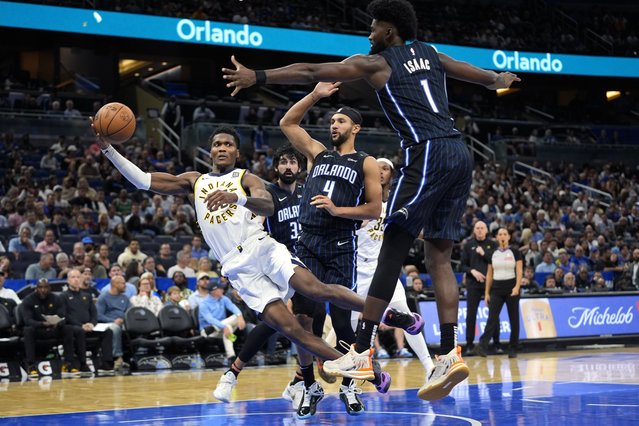 Indiana Pacers guard Bennedict Mathurin, center, dives between Orlando Magic guard Jalen Suggs (4) and forward Jonathan Isaac (1) to save the ball from going out of bounds during the second half of an NBA basketball game, Wednesday, November 13, 2024, in Orlando, Fla. (Photo by John Raoux/AP Photo)