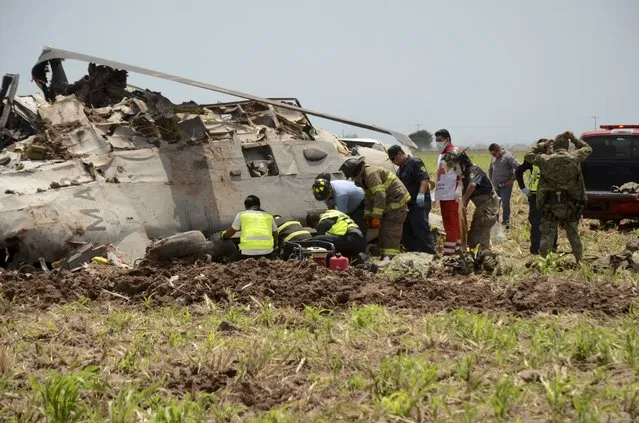 Emergency personnel work next to a navy Blackhawk helicopter crashed after supporting those who conducted the capture of drug lord Rafael Caro Quintero, near Los Mochis, Sinaloa state, Mexico, Friday, July 15, 2022. Mexico's navy said multiple people aboard died. (Photo by Guillermo Juarez/AP Photo)