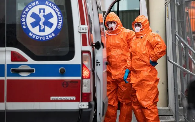 Medical staff in protective gear stand near an ambulance upon the arrival at the infectious ward of the Public Hospital in Lublin, Poland on March 12, 2020. (Photo by Jakub Orzechowski/Agencja Gazeta via Reuters)