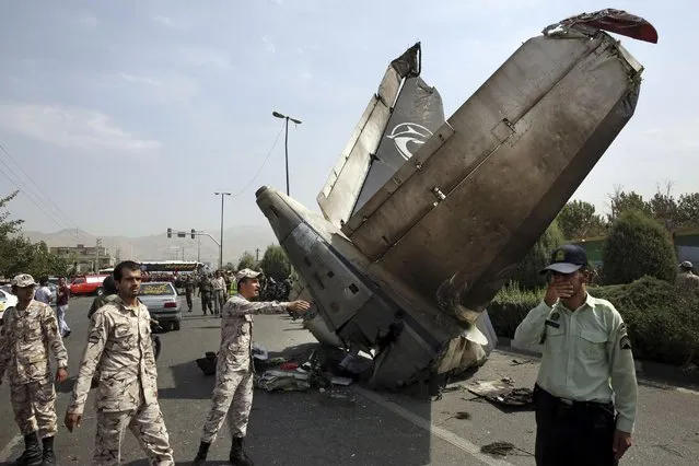 Iranian Revolutionary Guards and police officers inspect the site of a passenger plane crash near the capital Tehran, Iran, Sunday, August 10, 2014. An Iranian passenger plane crashed Sunday while taking off from an airport near the capital, Tehran, killing tens of people onboard, state media reported. (Photo by Vahid Salemi/AP Photo) 