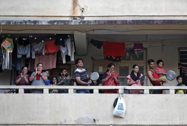 Residents clap and bang utensils from their balconies to cheer for emergency personnel and sanitation workers who are on the frontlines in the fight against coronavirus, in Mumbai, India, March 22, 2020. (Photo by Francis Mascarenhas/Reuters)