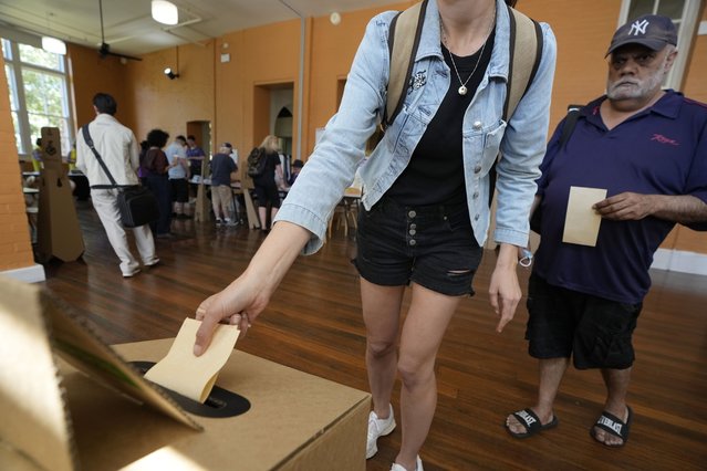 A man, right, waits as a woman drops her ballot into a box a polling place in Redfern as Australians cast their final votes in Sydney, Saturday, October 14, 2023, in their first referendum in a generation that aims to tackle Indigenous disadvantage by enshrining in the constitution a new advocacy committee. Australia will look for new ways to lift Indigenous living standards after voters soundly rejected a proposal to create a new advocacy committee, the deputy prime minister said on Sunday, Oct. 15. (Photo by Rick Rycroft/AP Photo)