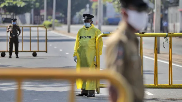 Sri Lankan police officers stand guard at a check point during a curfew imposed to stop spreading of a new virus in Colombo, Sri Lanka, Sunday, April 12, 2020. (Photo by Eranga Jayawardena/AP Photo)