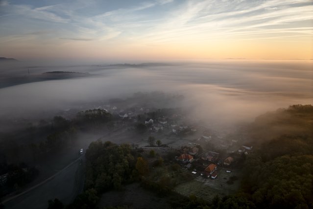 A picture taken with a drone shows the morning fog hovering above the landscape during sunrise as it is seen from Cered, northern Hungary, 22 October 2024. (Photo by Peter Komka/EPA/EFE)