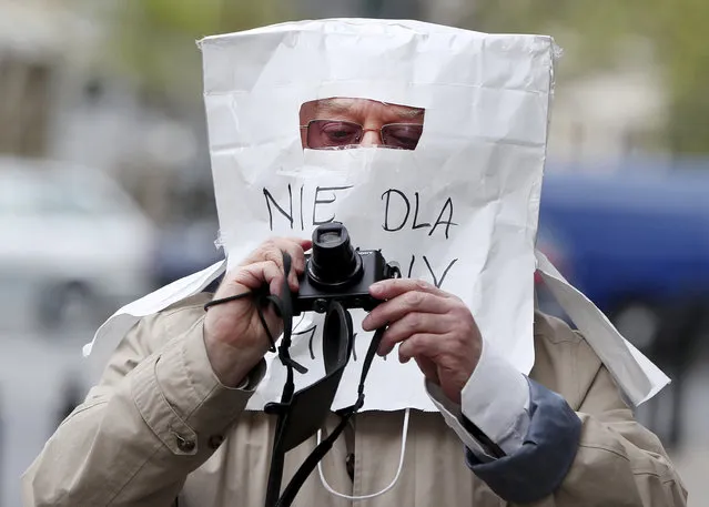 A photographer wearing an unusual protective mask against coronavirus spread made from a paper bag, in Warsaw, Poland, Sunday, April 19, 2020. (Photo by Czarek Sokolowski/AP Photo)