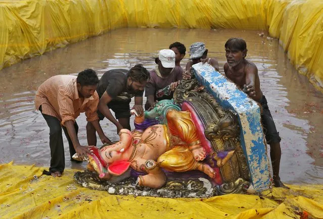Municipal workers prepare to lift an idol of the Hindu elephant god Ganesh, the deity of prosperity, from a pond after its immersion during the ten-day-long Ganesh Chaturthi festival in the western Indian city of Ahmedabad September 5, 2014. (Photo by Amit Dave/Reuters)