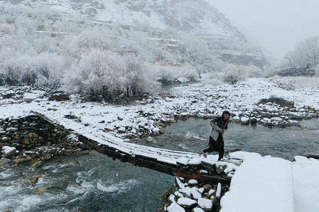 An Afghan boy walks across a footbridge during the first snowfall in the Dara district of Afghanistan's Panjshir province on December 2, 2024. (Photo by Shah Poor Afzally/AFP Photo)